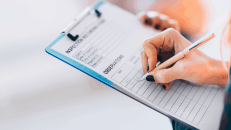 A female's hand is writing on a clipboard that says 