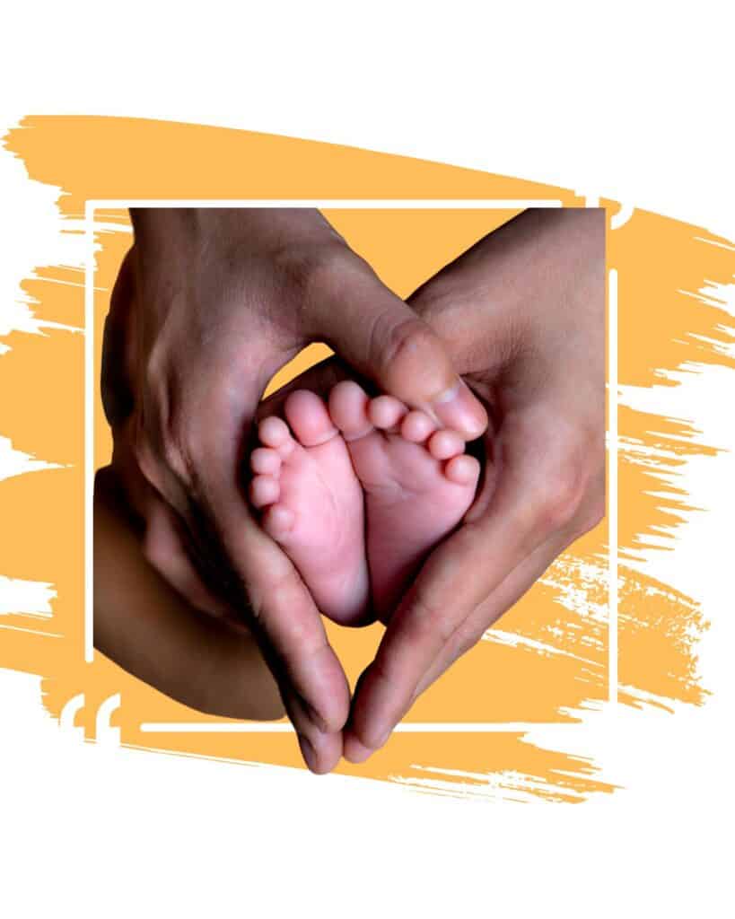 Hands holding baby feet on a yellow backgound