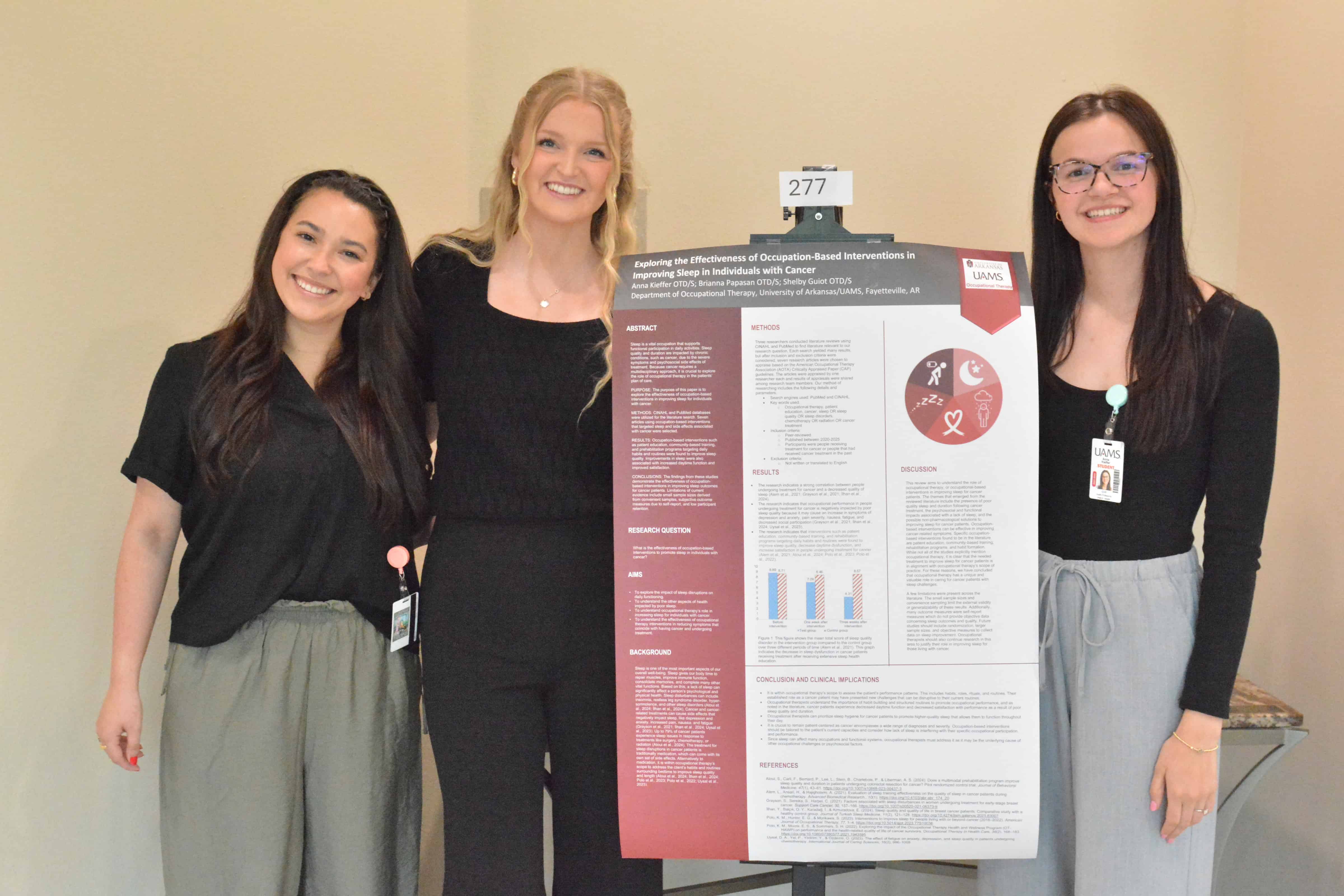 A group of 3 female students standing next to a poster