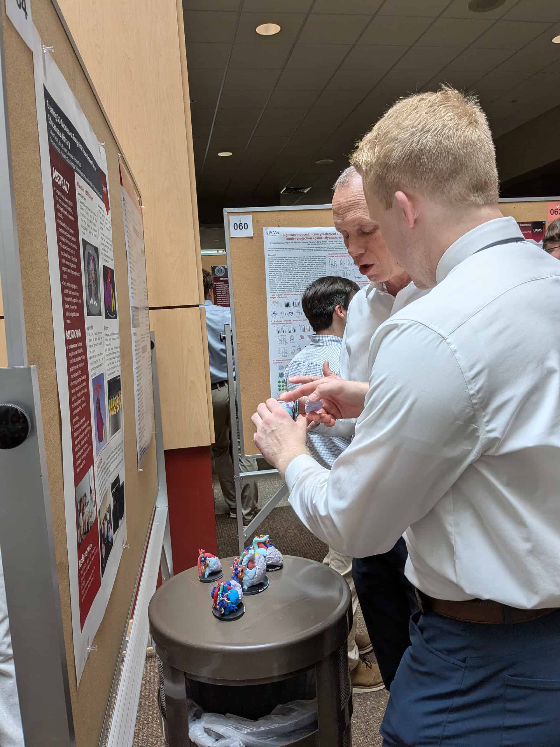 A student in front of a poster holding a model and explaining it to an audience