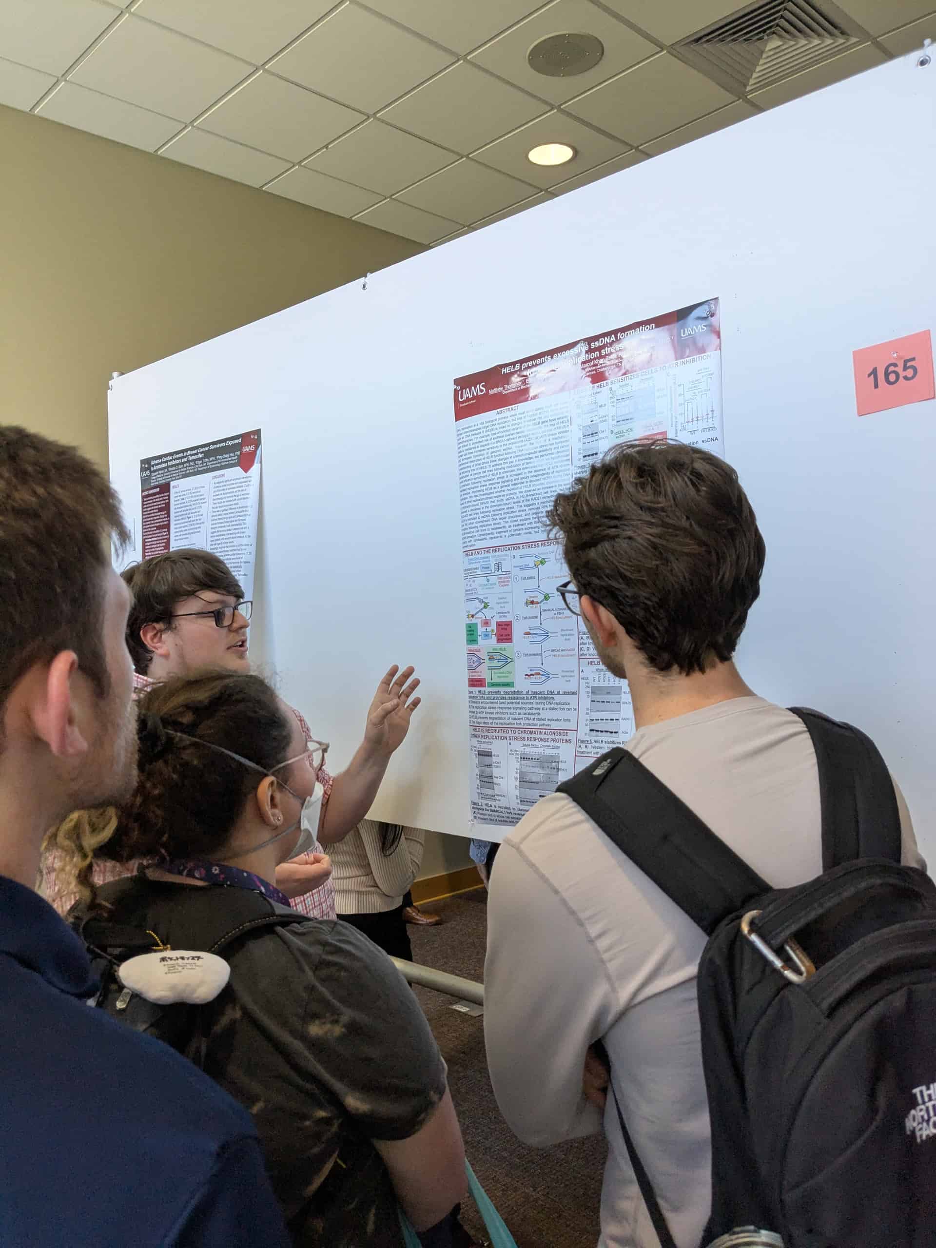 4 Students in front of a poster