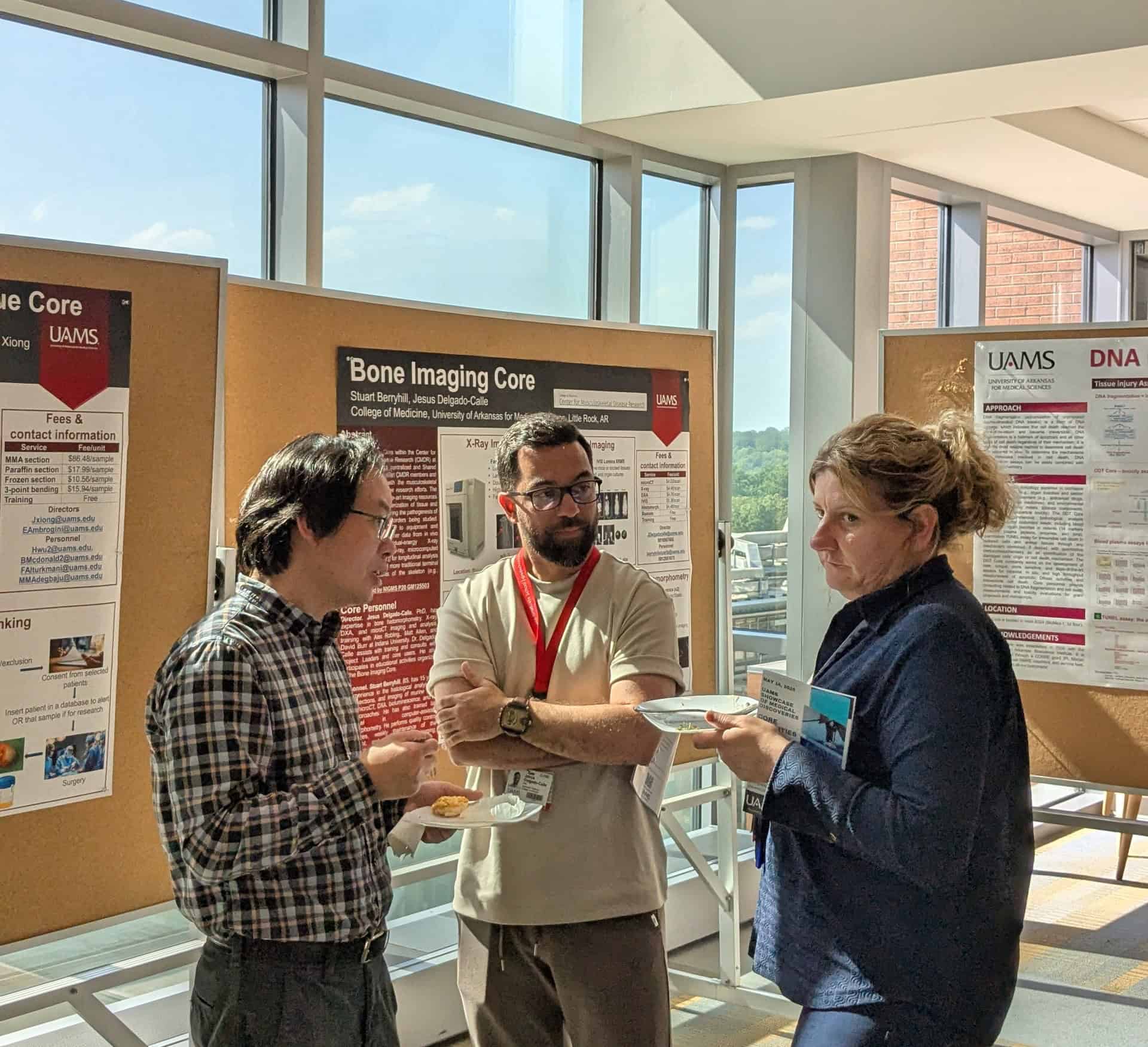 3 researchers are talking in front of a poster
