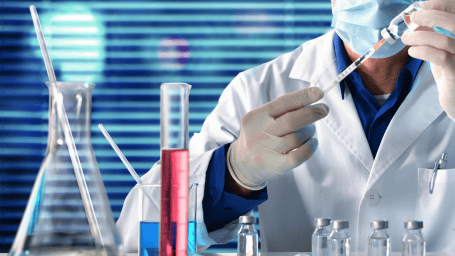 Photo of test tubes, a beaker, and a magnifying glass on a navy background.