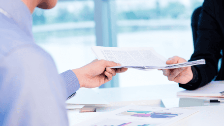 Someone is handing a piece of paper to another person