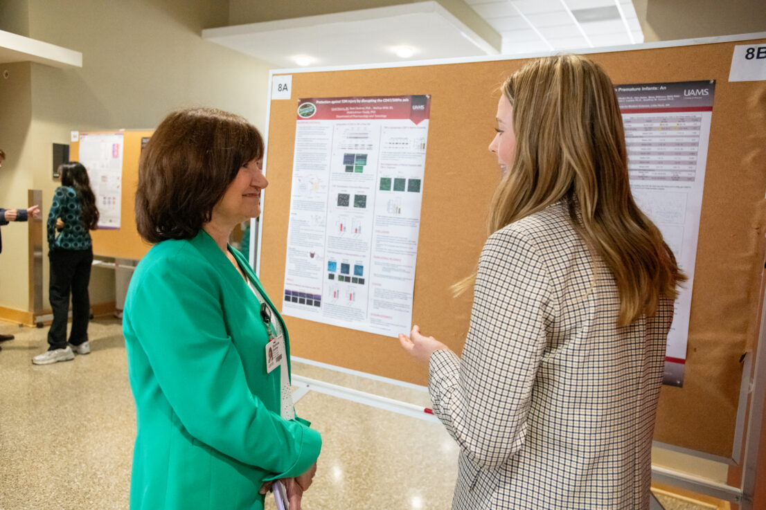 Dr. Gardner is listening to a student presenting a poster